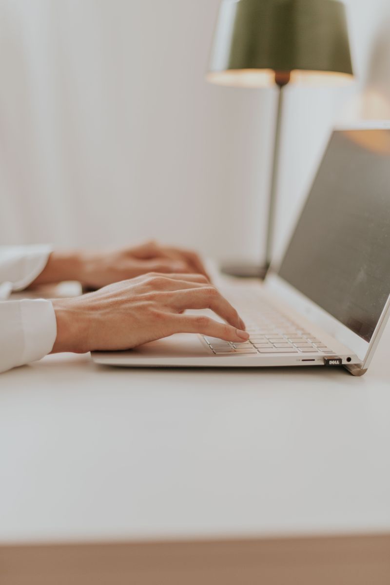 Close-up of hands typing on a laptop keyboard at a minimalist desk