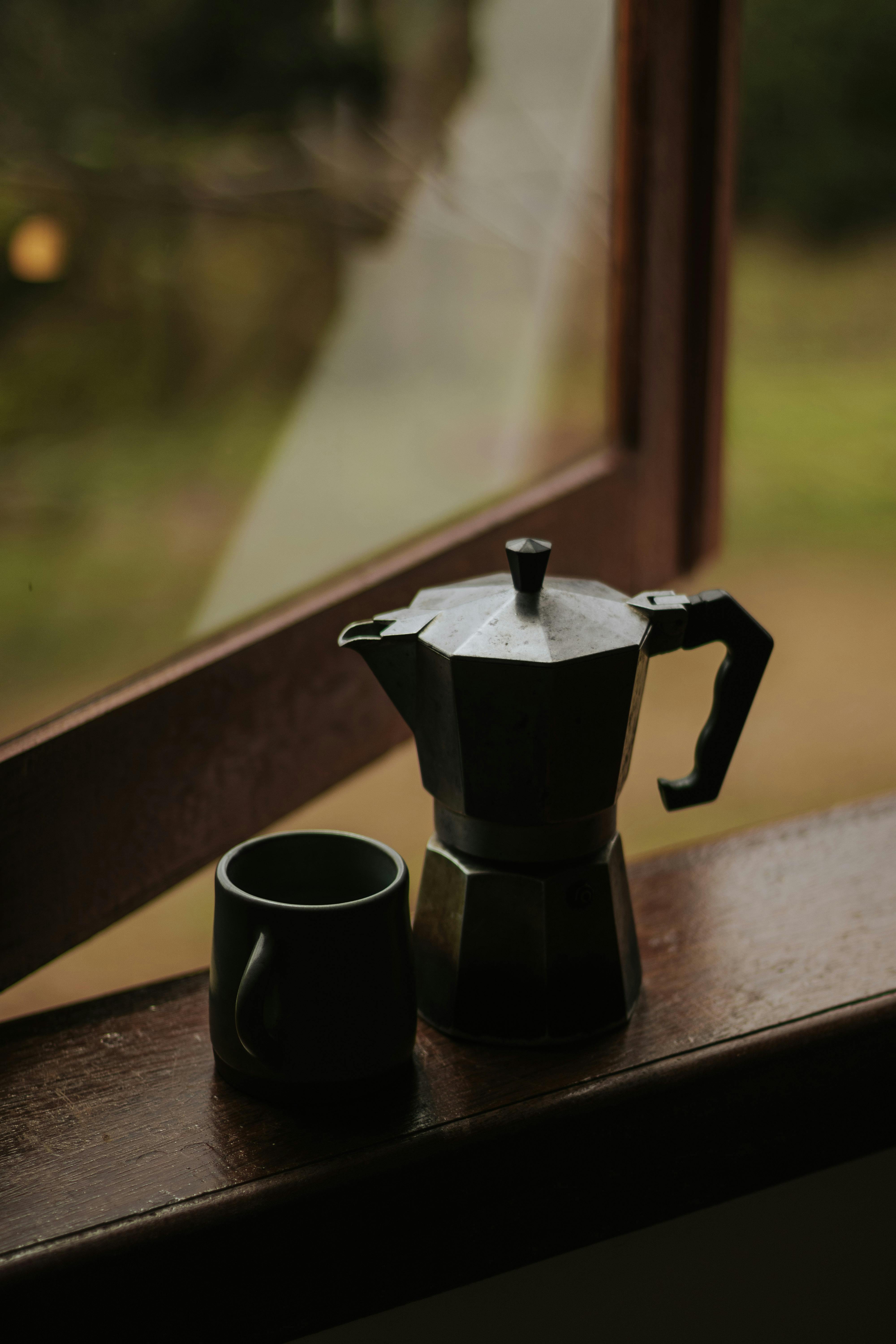 A tranquil coffee scene with a moka pot and cup on a windowsill in Brazil.