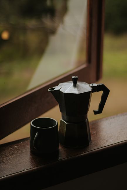 A tranquil coffee scene with a moka pot and cup on a windowsill in Brazil.