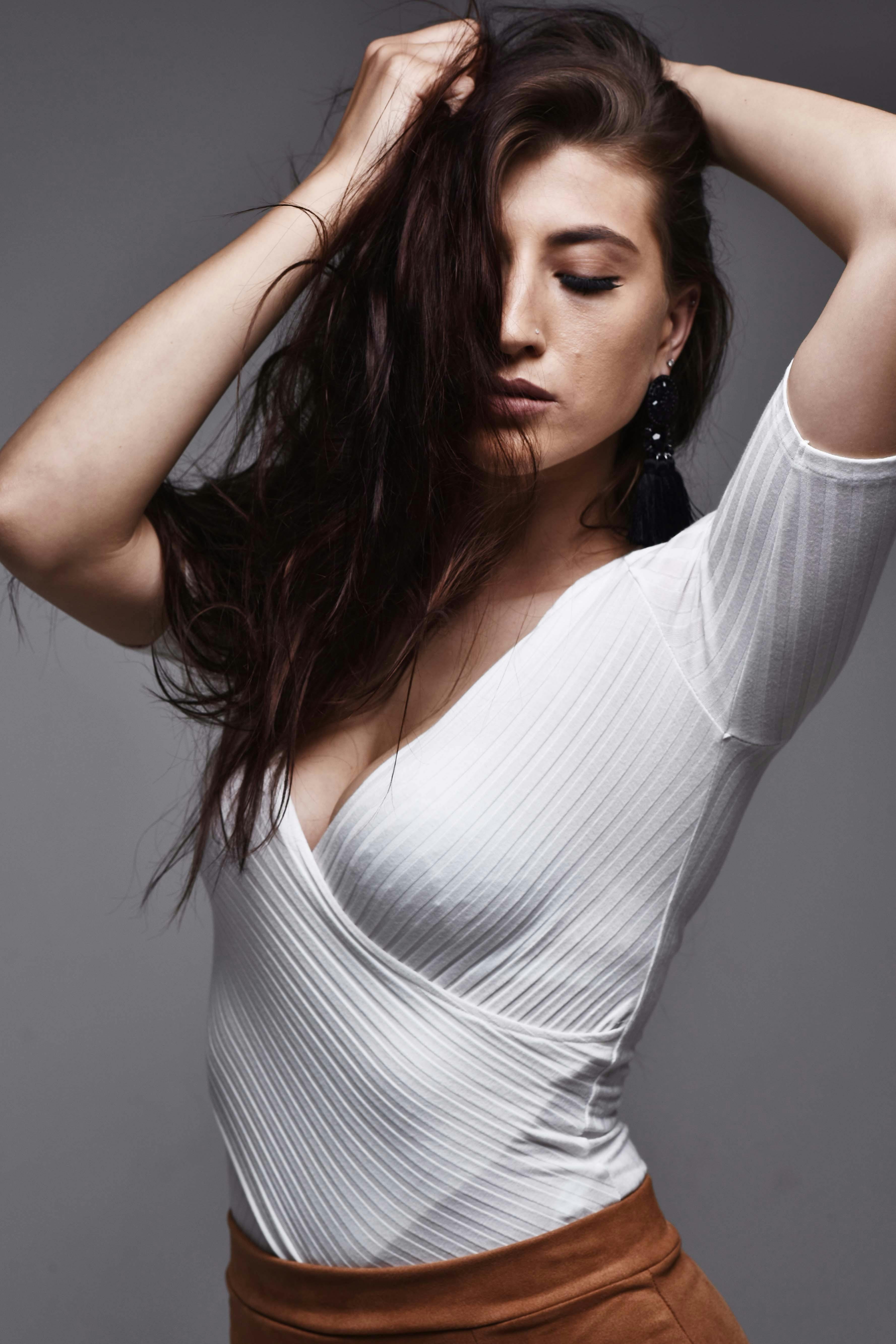 Sophisticated portrait of a woman posing in a studio wearing a white V-neck top.