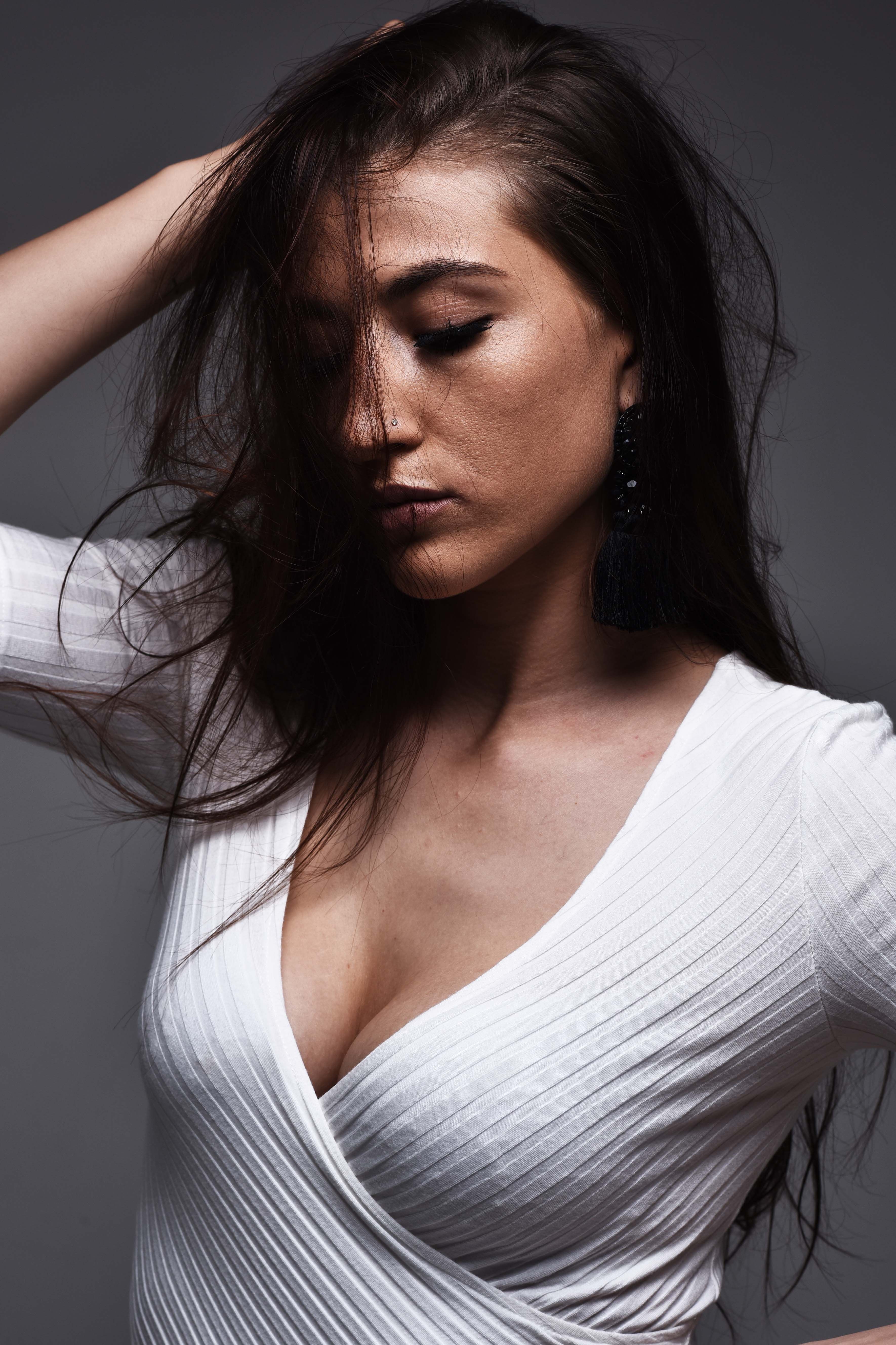Stylish portrait of a woman with textured hair and a white V-neck dress in a studio setting.