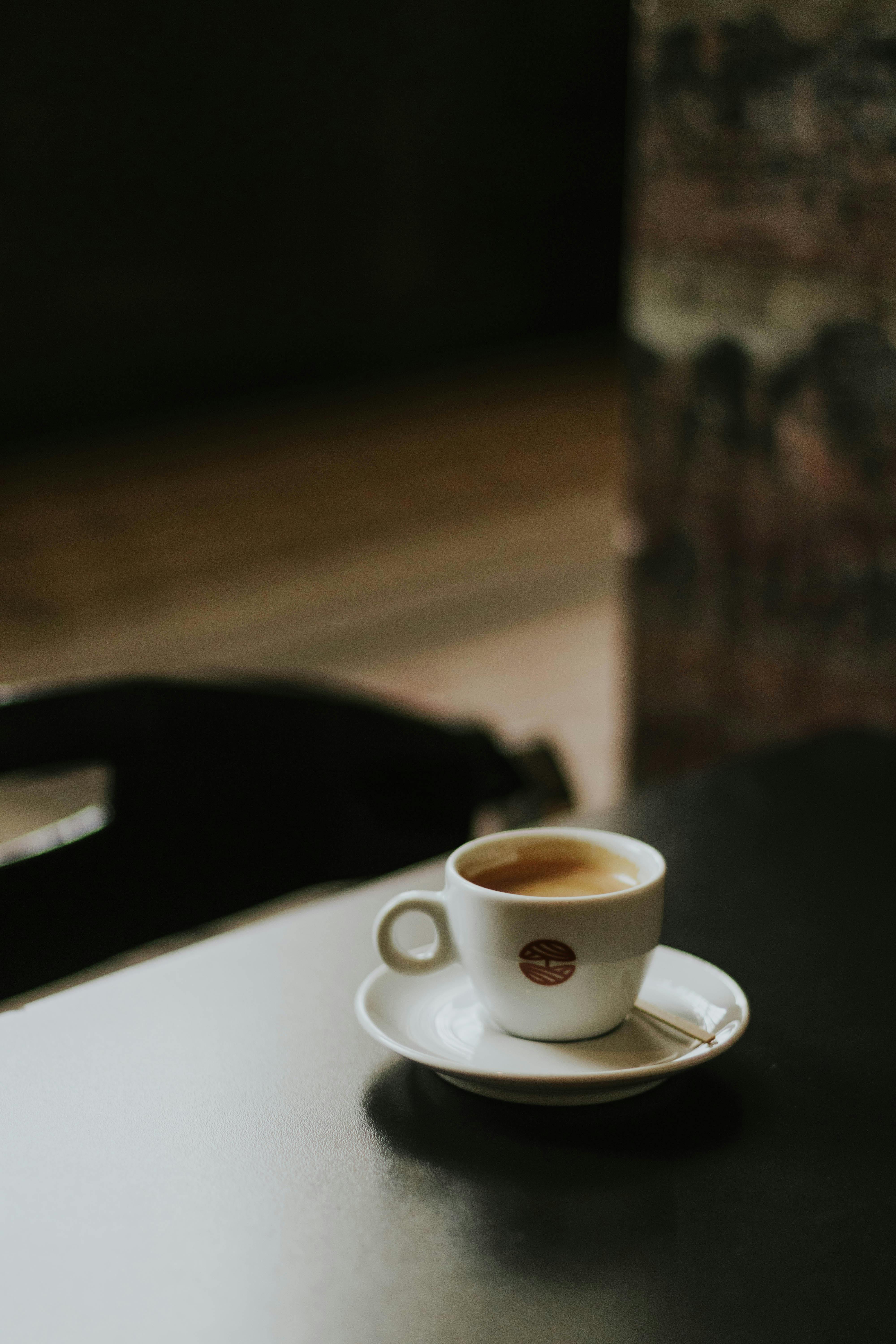 A warm espresso cup sits invitingly on a table in a dimly lit cafe, evoking comfort.
