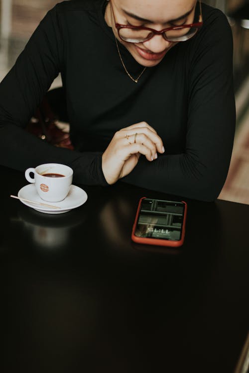 Free A woman sitting at a table with a cup of coffee Stock Photo