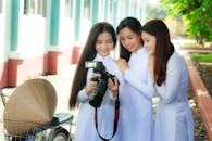 Photo of Three Women in White Outfits Checking Photos on The Screen of a DSLR camera.