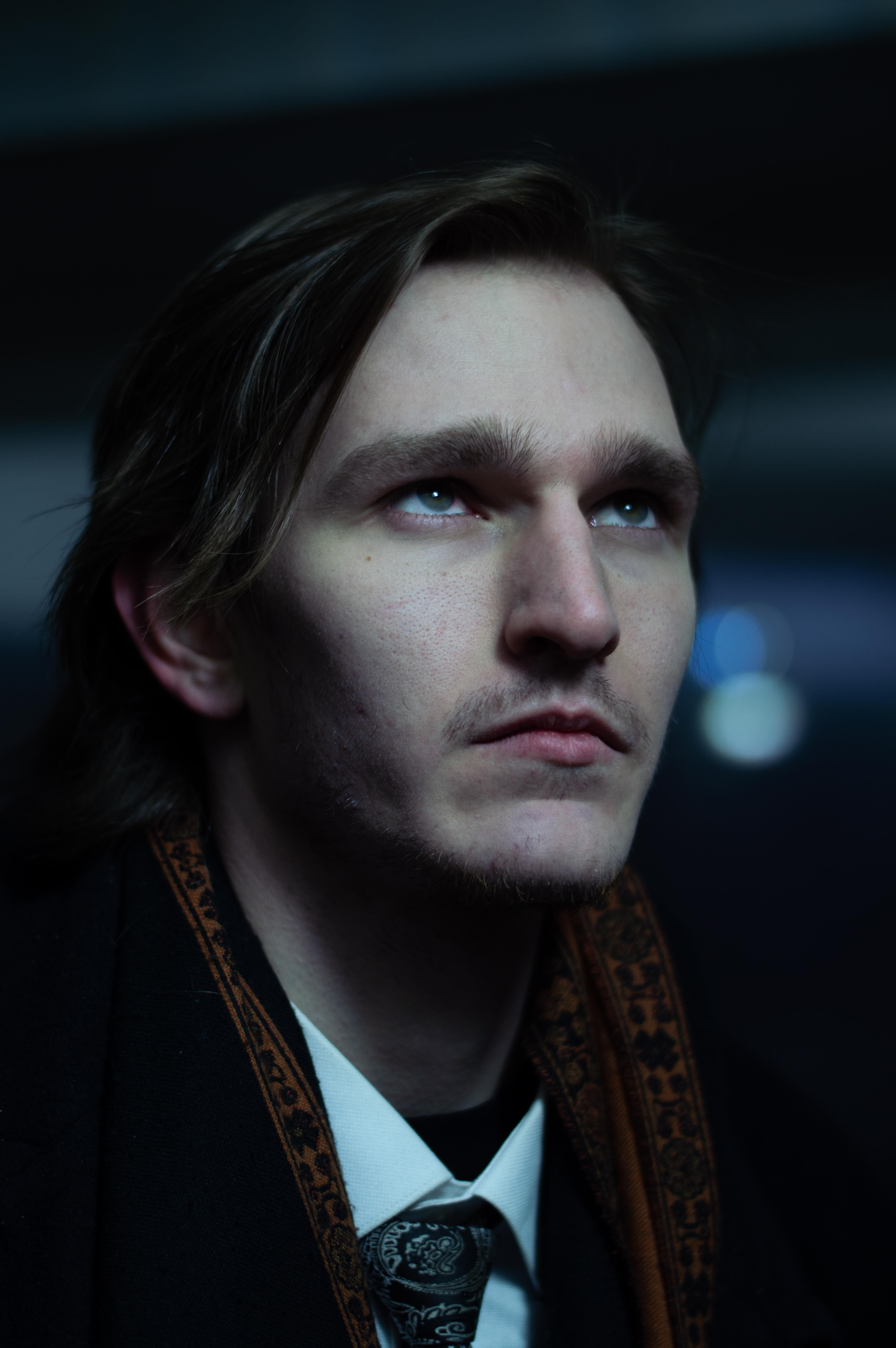 Elegant portrait of a man looking upward, wearing a necktie and scarf.