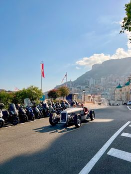 Classic car driving on a sunny day in Monaco, overlooking the city's stunning landscape.