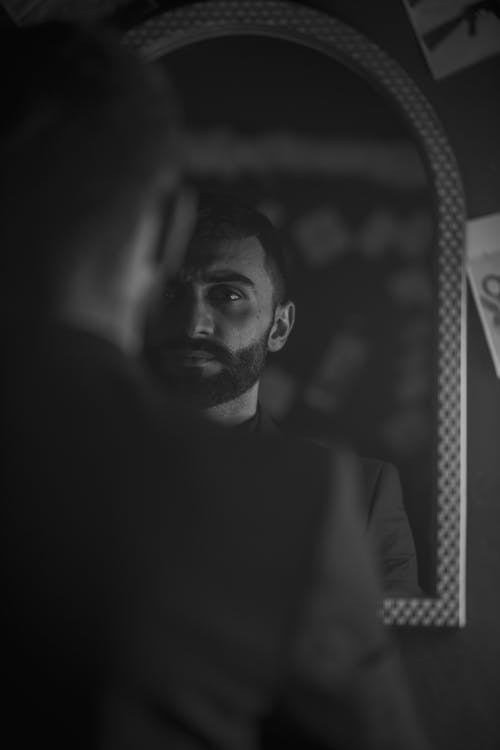 A man in a suit looking in the mirror