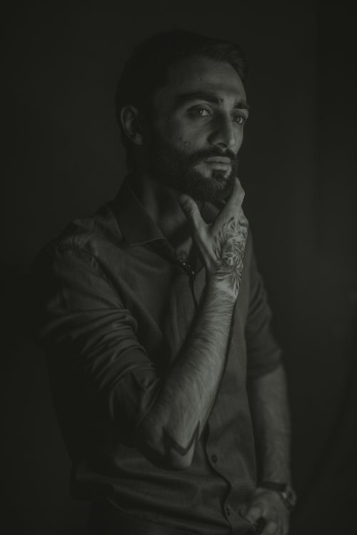 Free A dramatic monochrome portrait of a man with beard and tattoos, highlighting contemplation and depth. Stock Photo