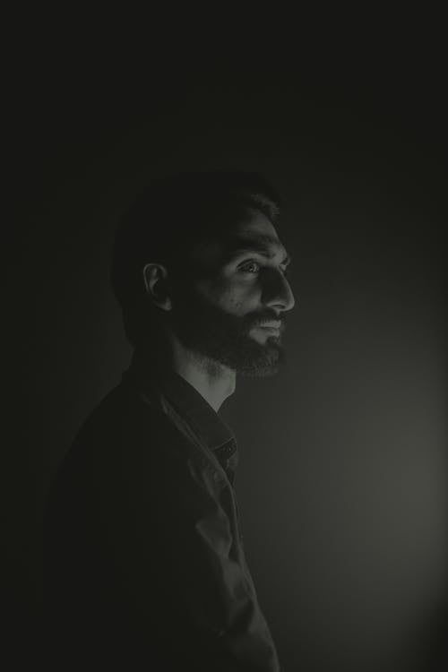 A man in black and white standing in the dark