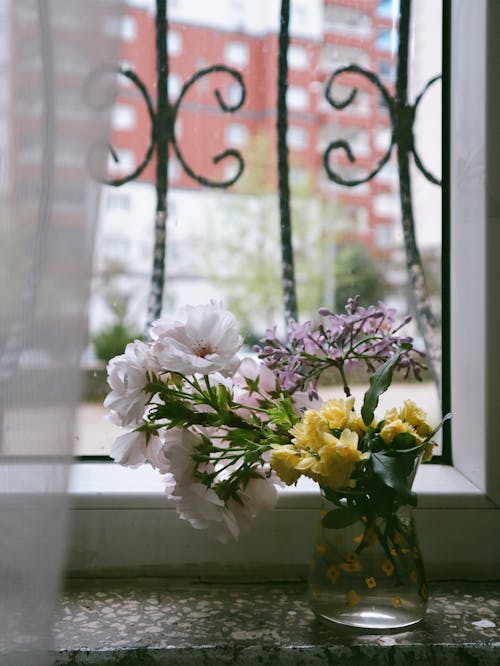 A vase with flowers in it sitting on a window sill