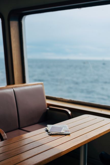 Tranquil sea view from a ferry window with a wooden table and documents. Perfect travel scene.