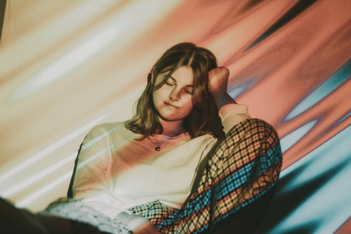 Free A woman laying down on a couch with a colorful background Stock Photo