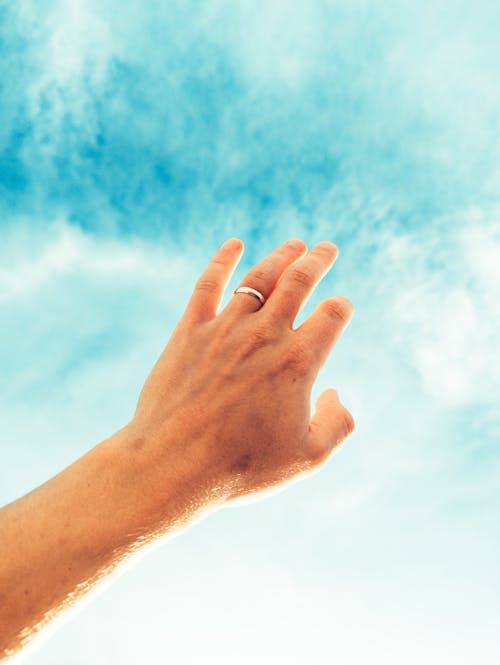 A person's hand reaching up to the sky