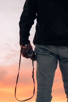 Back view of a person holding a camera against a stunning sunset sky.