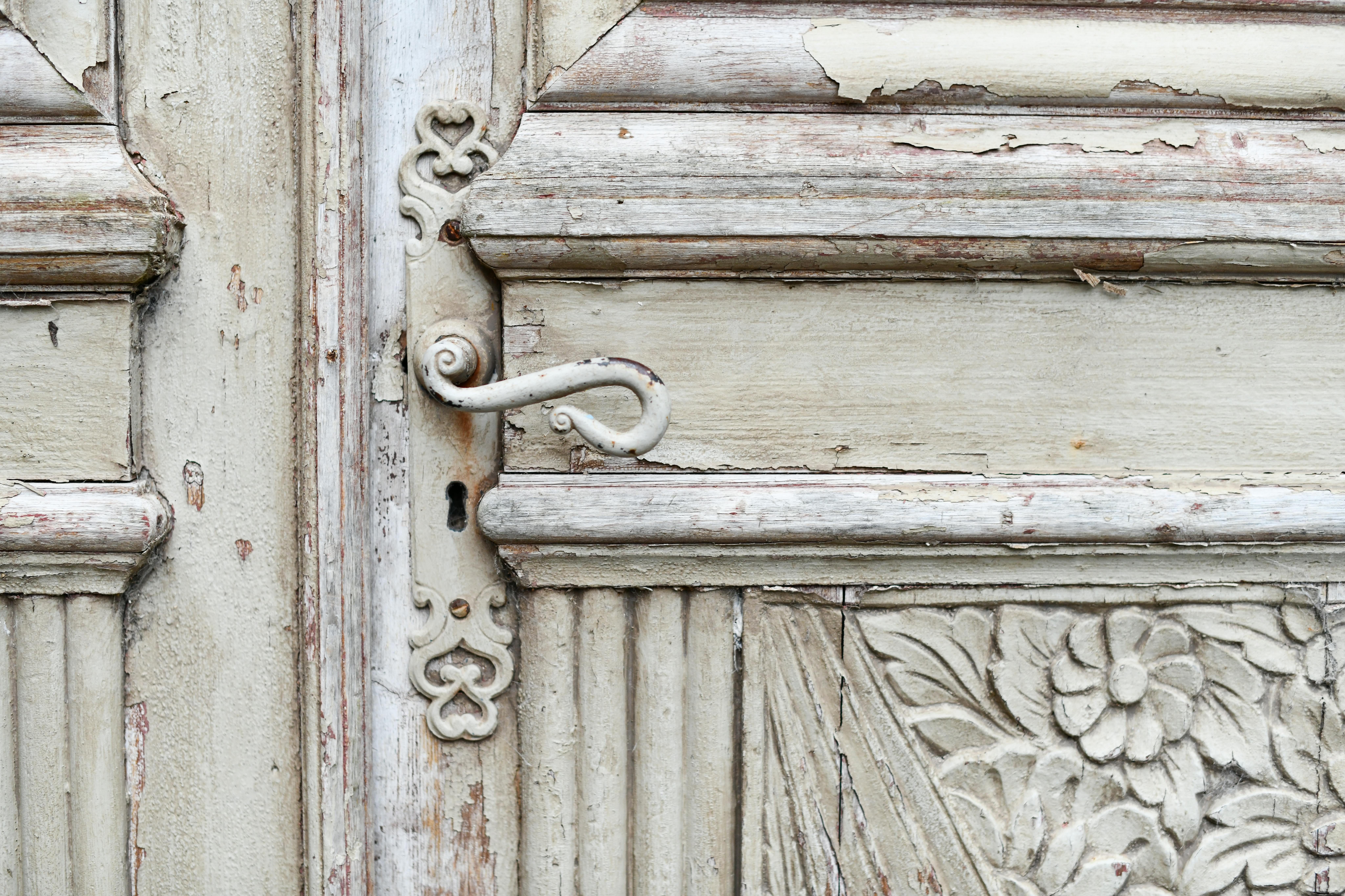 Close-up view of an old, decorative wooden door with an ornate handle and floral carvings.