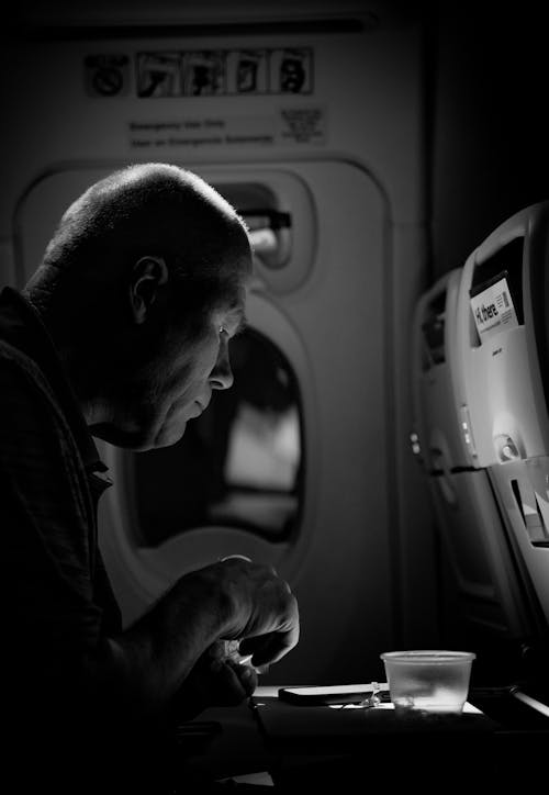 A man sitting in an airplane eating his food