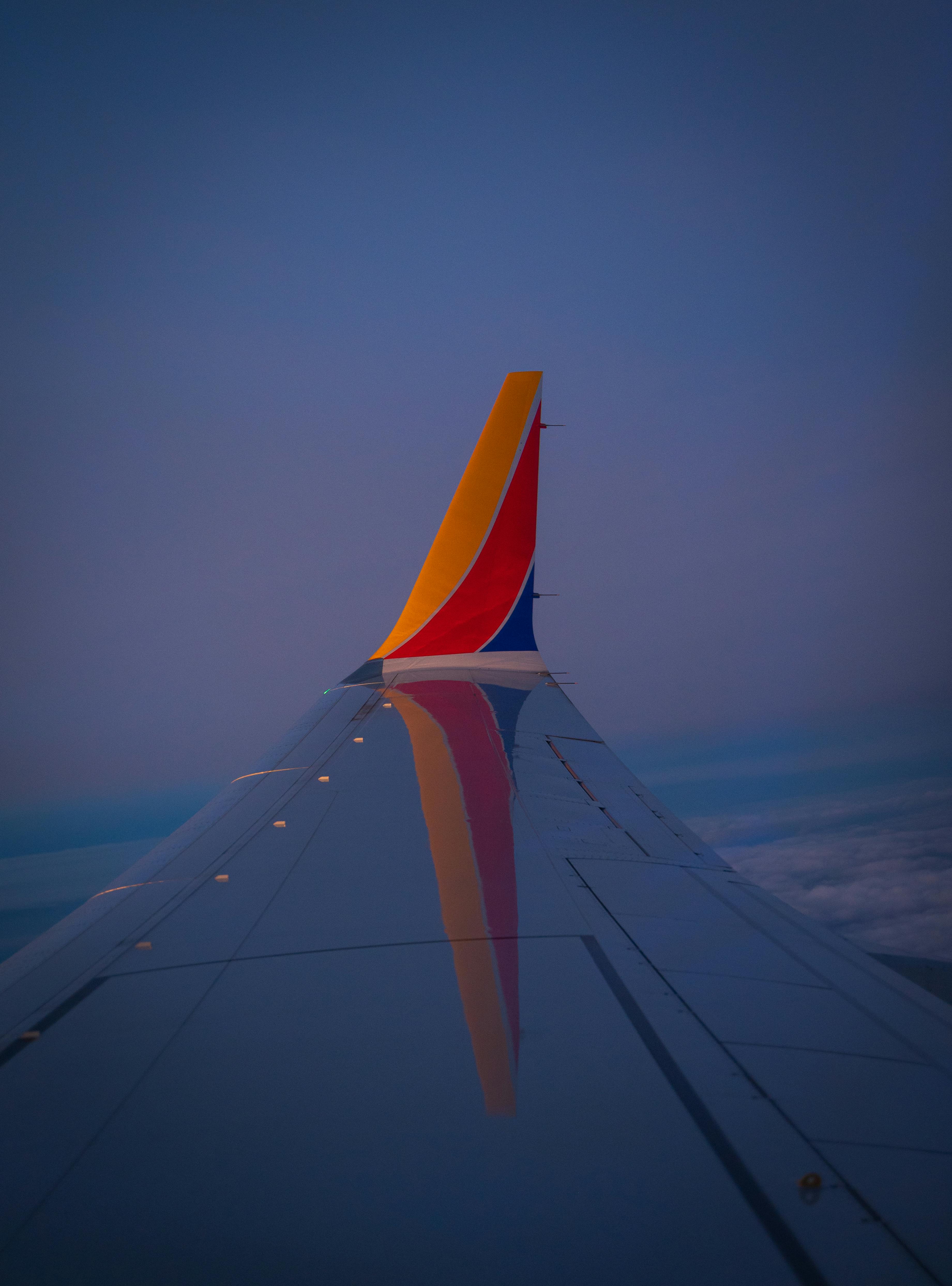 View from an airplane wing at dusk, capturing a serene sky and vibrant tail colors.