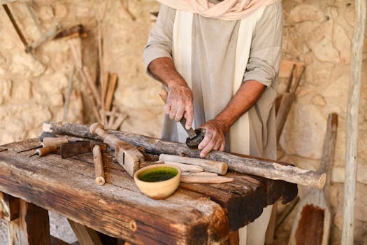 An artisan works skillfully with wooden tools in a rustic workshop environment.