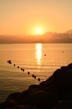 Peaceful sunrise casting warm light over the calm sea with beautiful reflections.