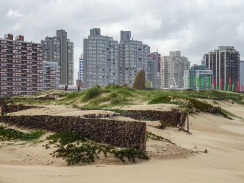 Free Dynamic cityscape of Punta del Este with sandy dunes and modern architecture under a cloudy sky. Stock Photo