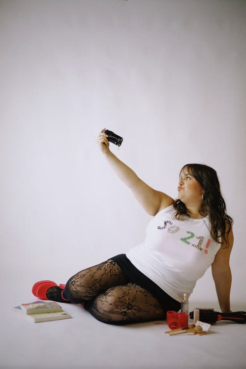 A woman sitting on the floor taking a picture of herself