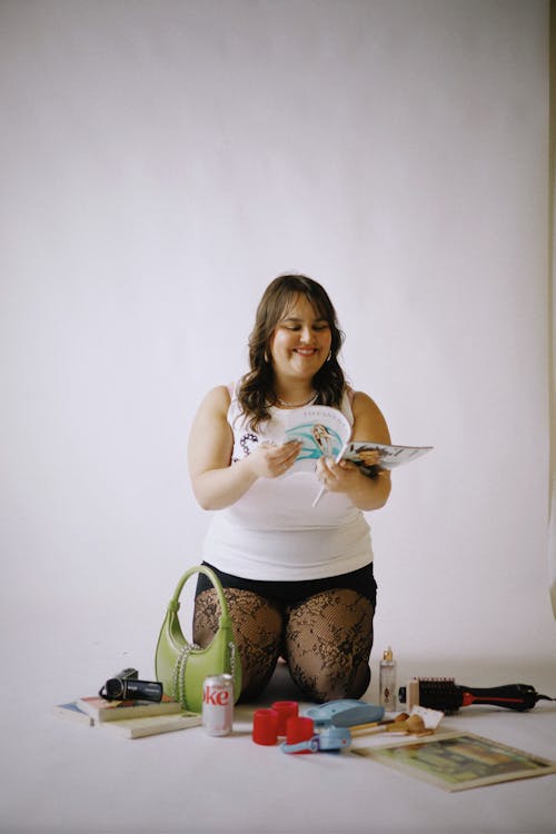 A woman sitting on the floor with a book and a magazine