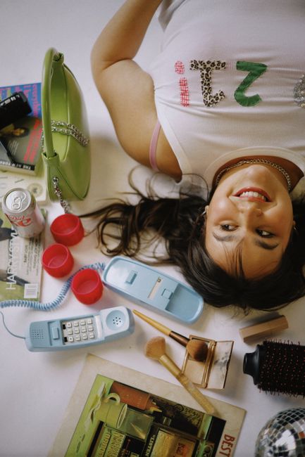 A young woman lying down with retro telephone and makeup on a white background.