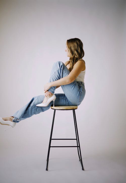 A woman sitting on a stool with her legs crossed