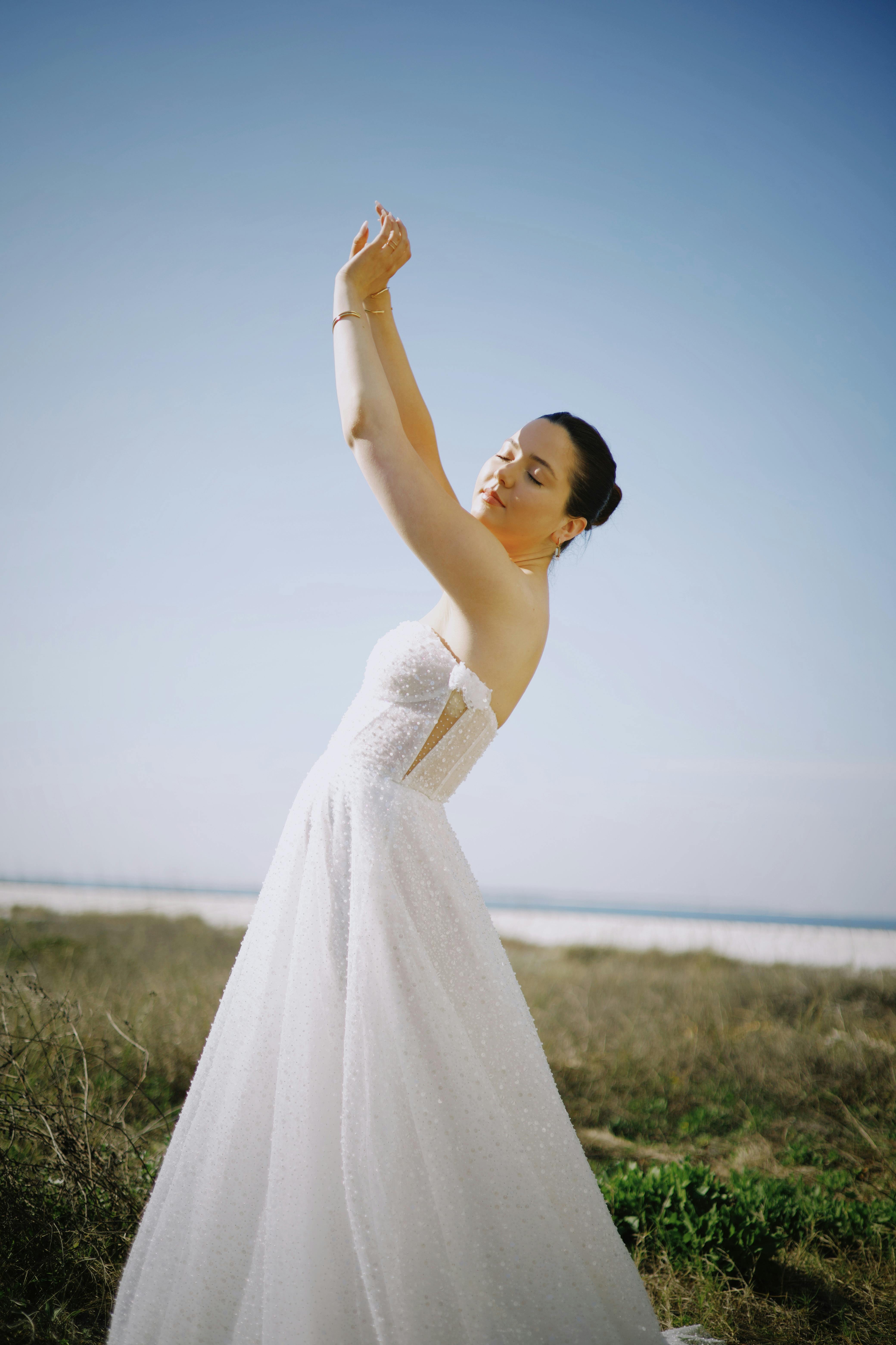 A bride gracefully posing outdoors in a beautiful wedding dress.