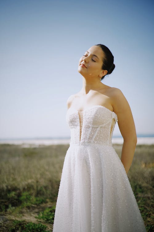 A woman in a wedding dress standing in the grass
