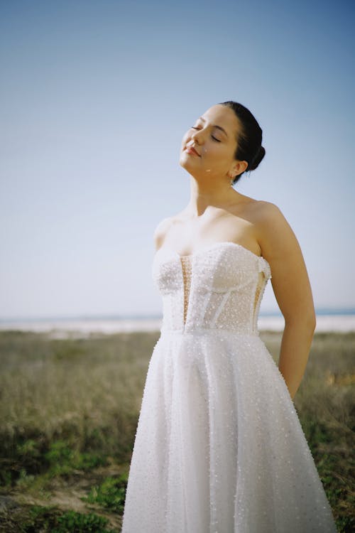 Free A woman in a wedding dress standing in the grass Stock Photo