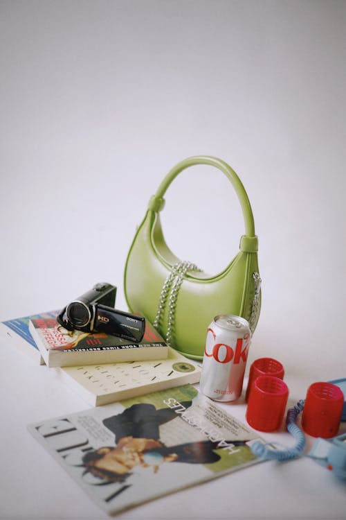 A green purse with a magazine and a book