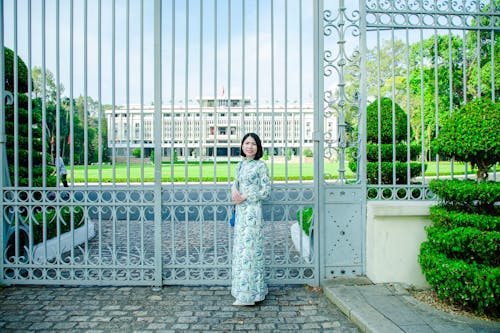 A woman in a long dress standing in front of a gate