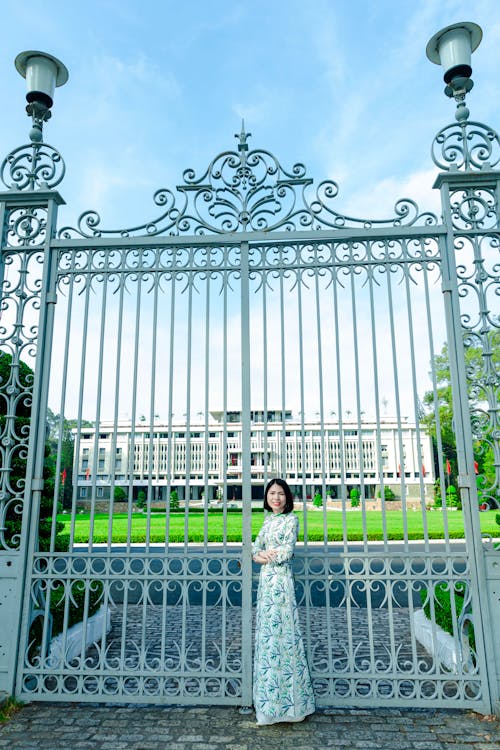 A woman in a long dress standing in front of a gate