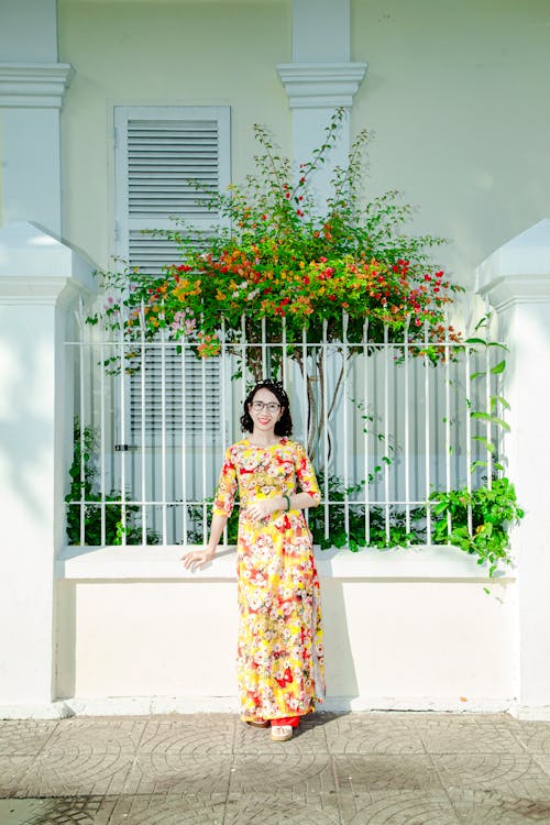 A woman in a yellow dress standing near a fence