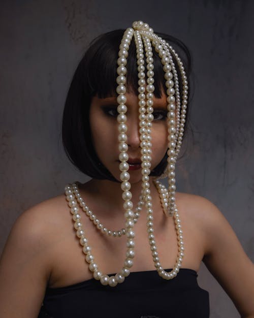 A woman with a pearl necklace and a black dress