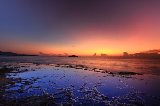 宁静的海滨，岩石倒映着五颜六色的天空，呈现出一场令人叹为观止的日落