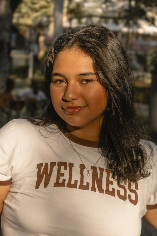 A woman wearing a wellness shirt posing for a photo