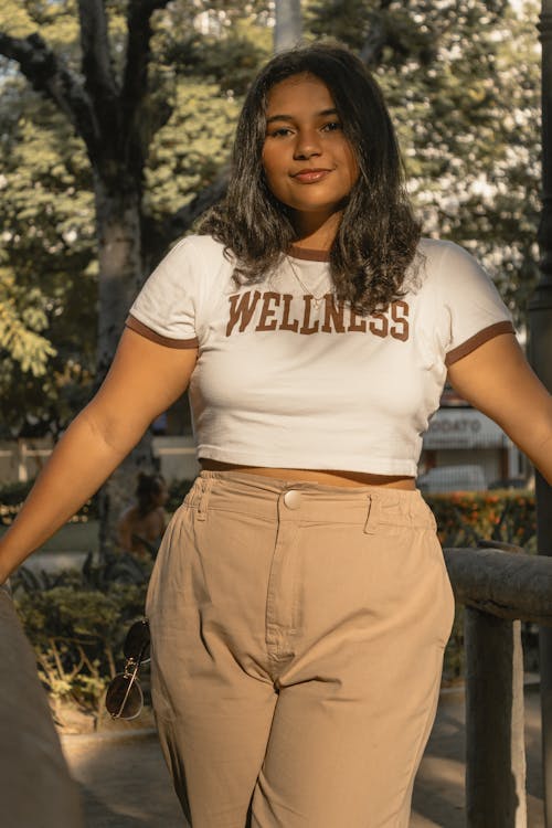 A woman in a white crop top and tan pants