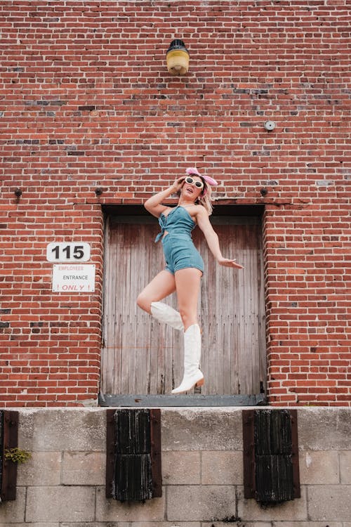 Free A woman in a blue dress and white boots is jumping Stock Photo