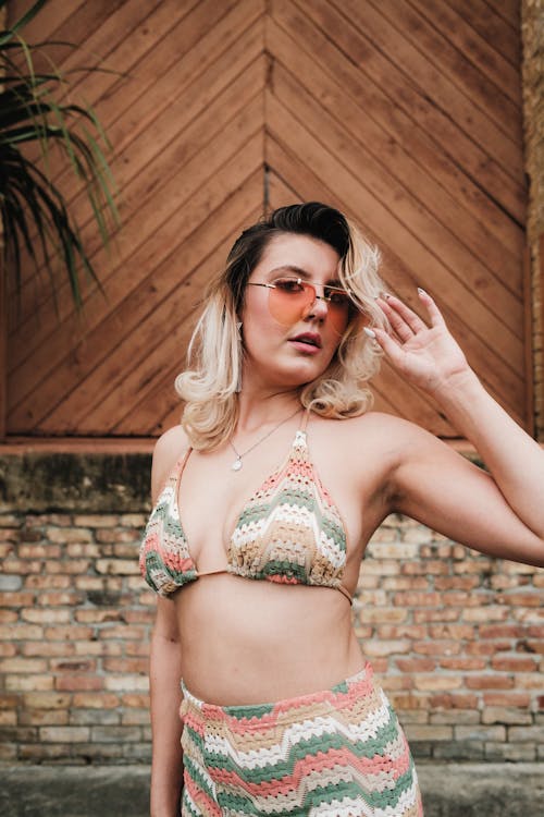 A woman in a bikini and sunglasses posing for the camera