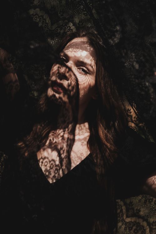 Free A woman silhouetted in an artistic shadow cast by lace, creating a mysterious and intriguing portrait. Stock Photo