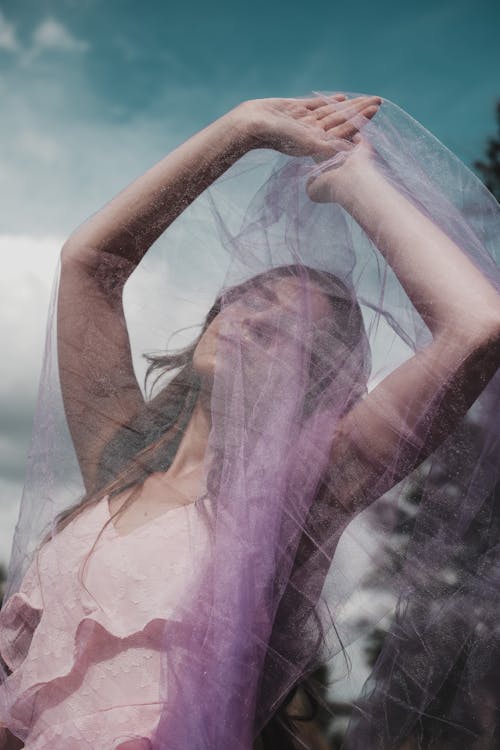 A woman in a purple dress is holding a veil