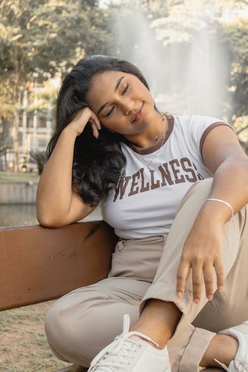 Free A woman sitting on a bench with her hands on her head Stock Photo