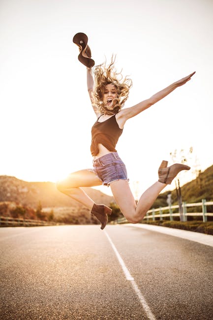 Woman Jumps on Grey and White Road during Golden Hour