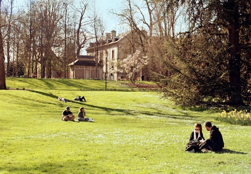 A group of people sitting in the grass near a building