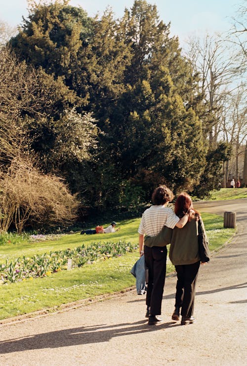 Two people walking down a path in a park