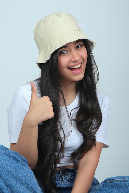 A young woman wearing a hat and giving the thumbs up