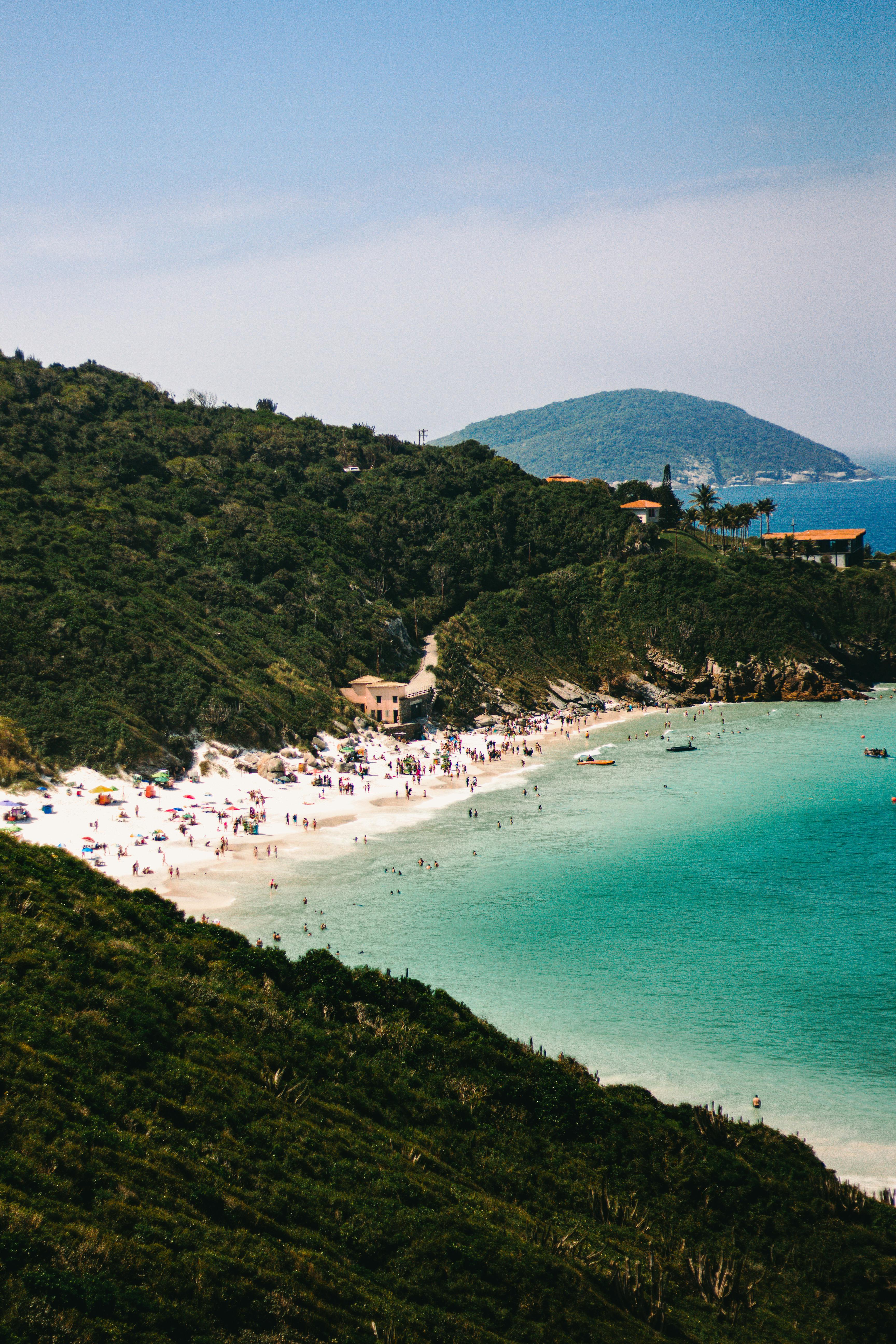 Vibrant tropical beach landscape, captured from above, showcasing turquoise waters, lush greenery, and sunbathers enjoying summer.