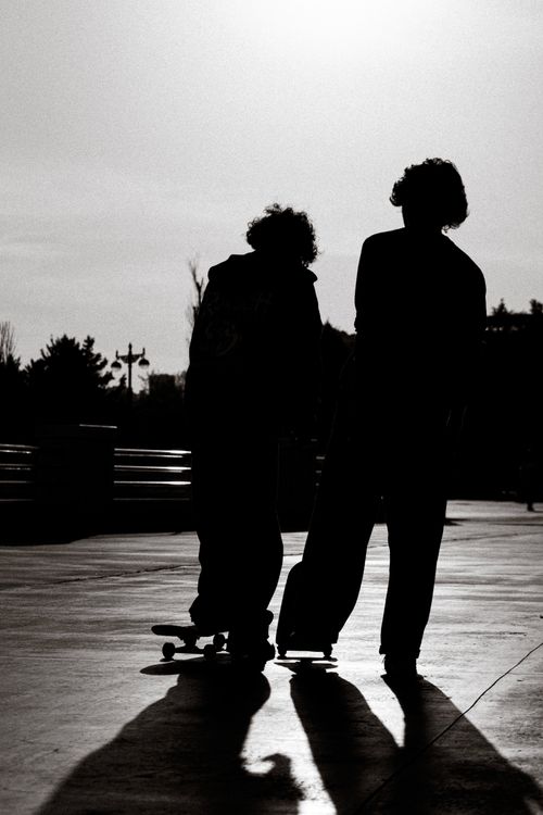 Free Silhouettes of two people with skateboards in an urban skatepark setting. Stock Photo